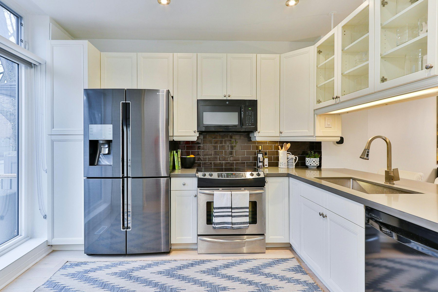 A kitchen with a stainless french-door refrigerator, range, microwave and dishwasher